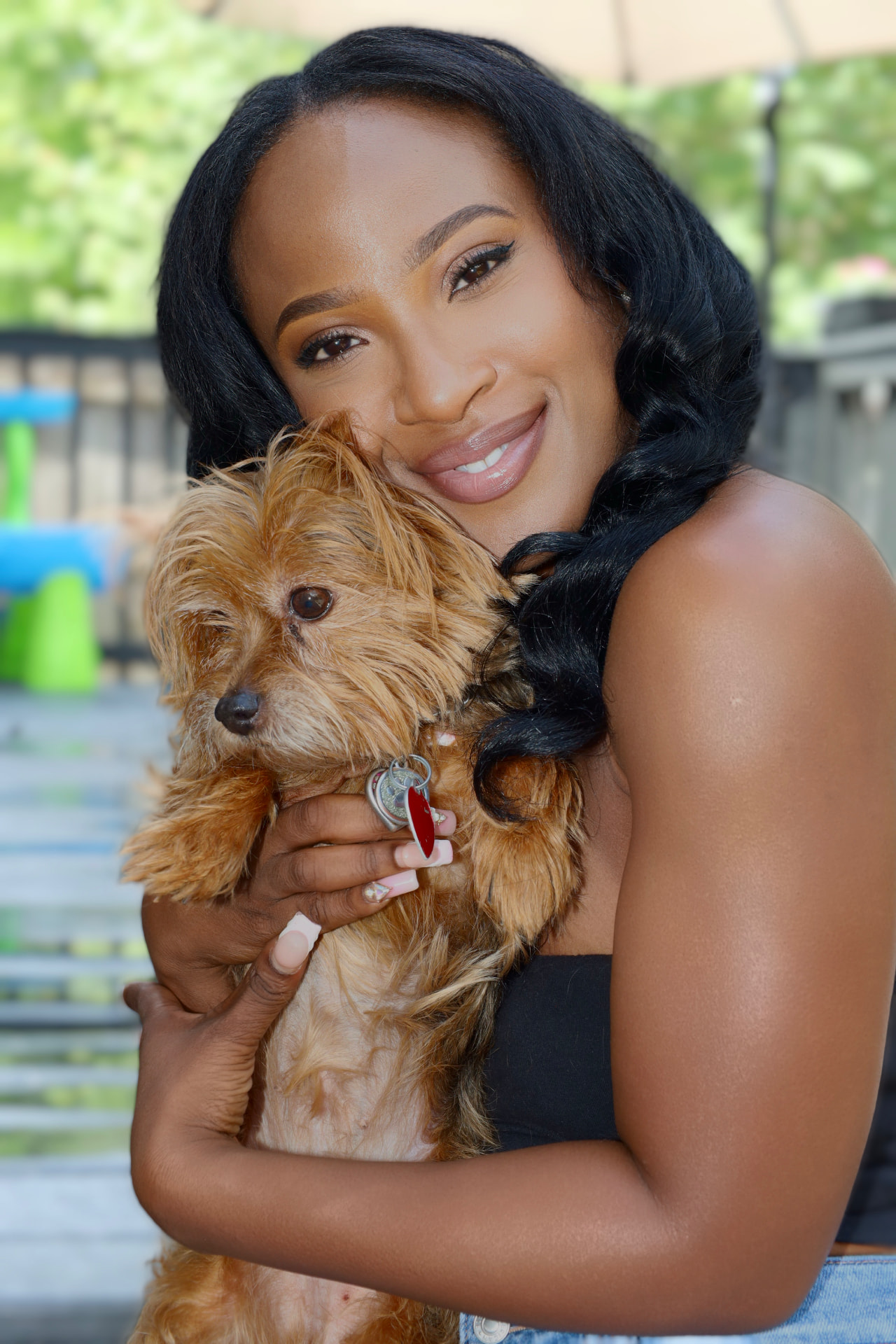 Daphne smiling outdoors holding her Yorkie, Scarlette